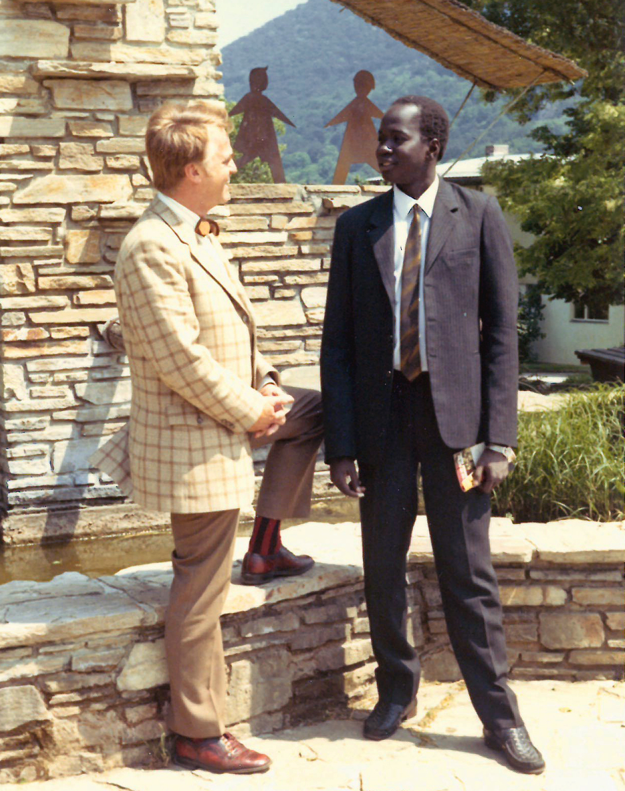 Zwei Männer in Anzügen vor einem SOS-Kinderdorf-Logo aus Metall
