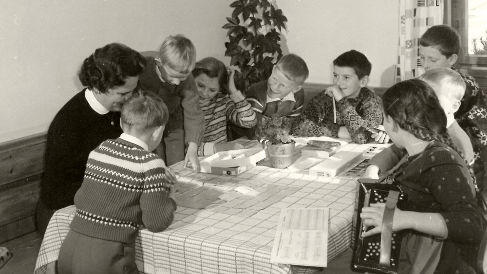 schwarz-weiß-foto von kindern, die um einen tisch herum sitzen
