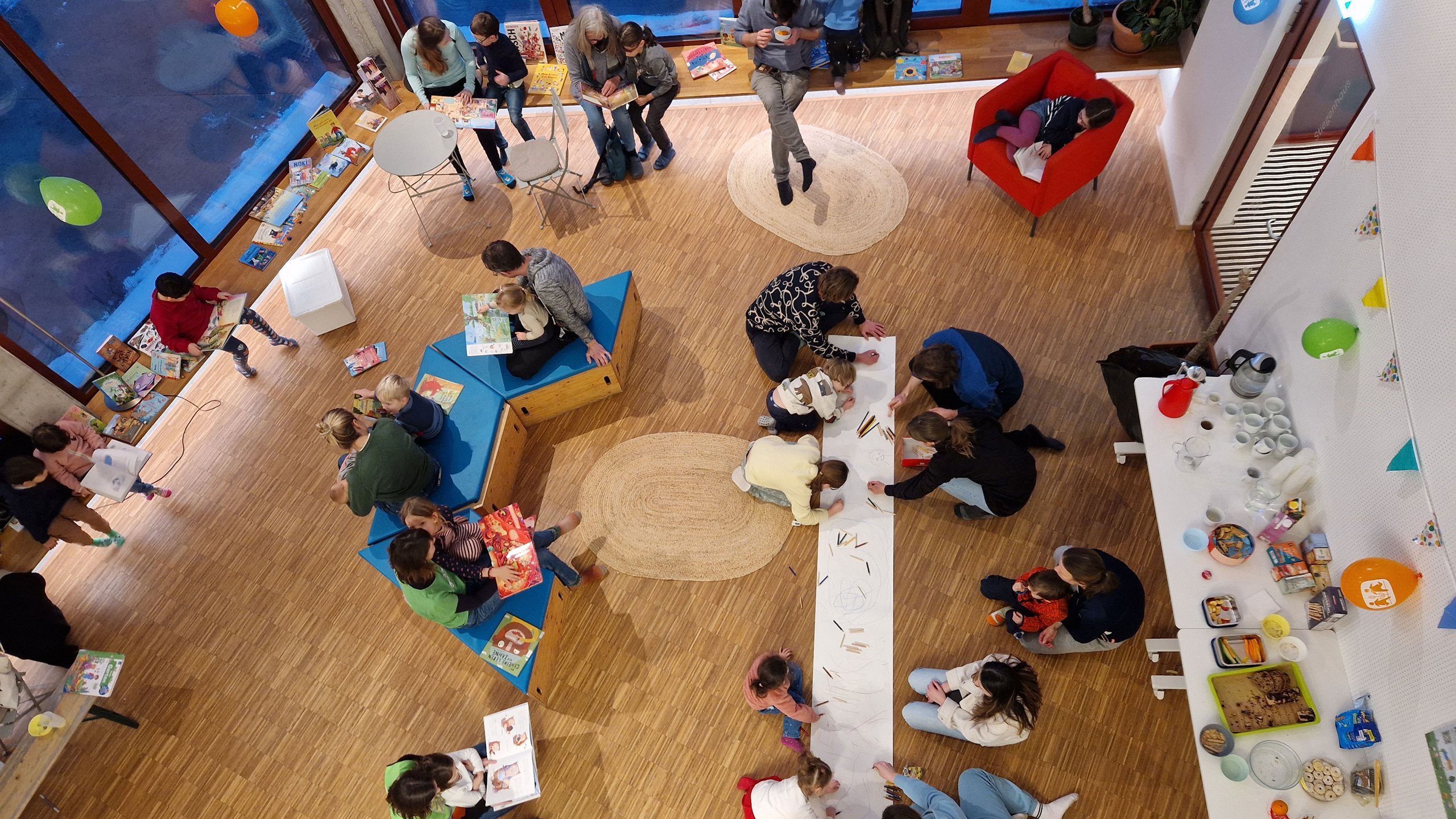 Kinder lesen mit Erwachsenen oder Malen auf großem Plakat gemeinsam