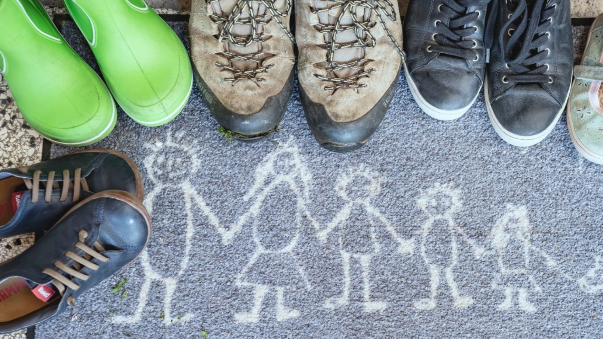 Fußmatte mit unterschiedlichen Schuhpaaren von groß bis klein