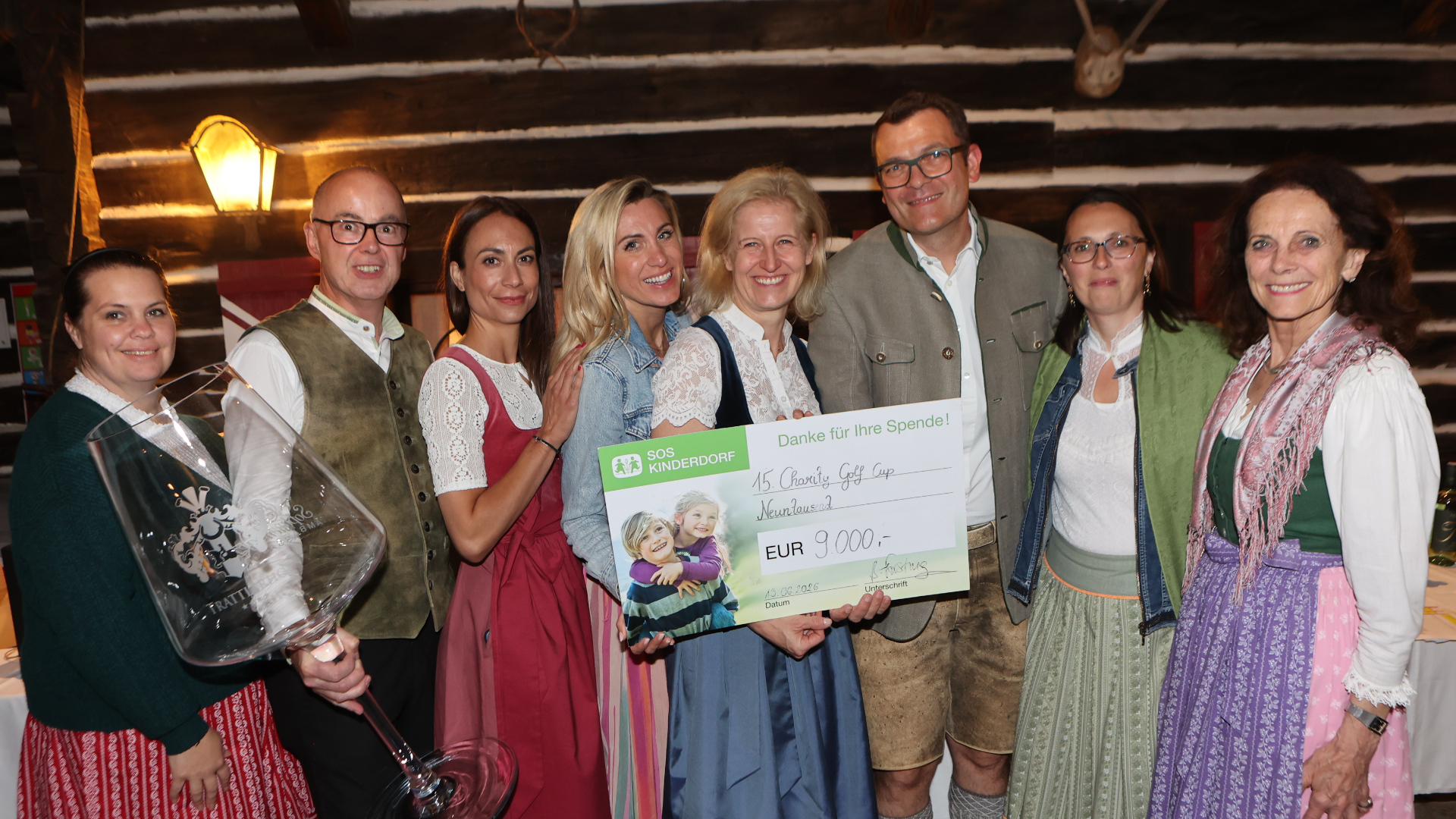 Gruppenfoto des 15. Trattlerhof Charity-Events bei dem die Person in der Mitte einen großen Scheck in der Hand hält
