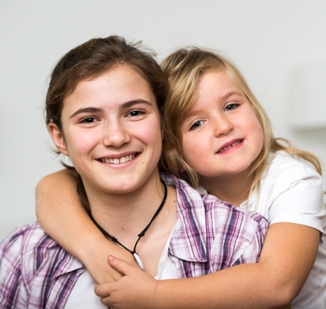 Mädchen umarmt ihre größere Schwester