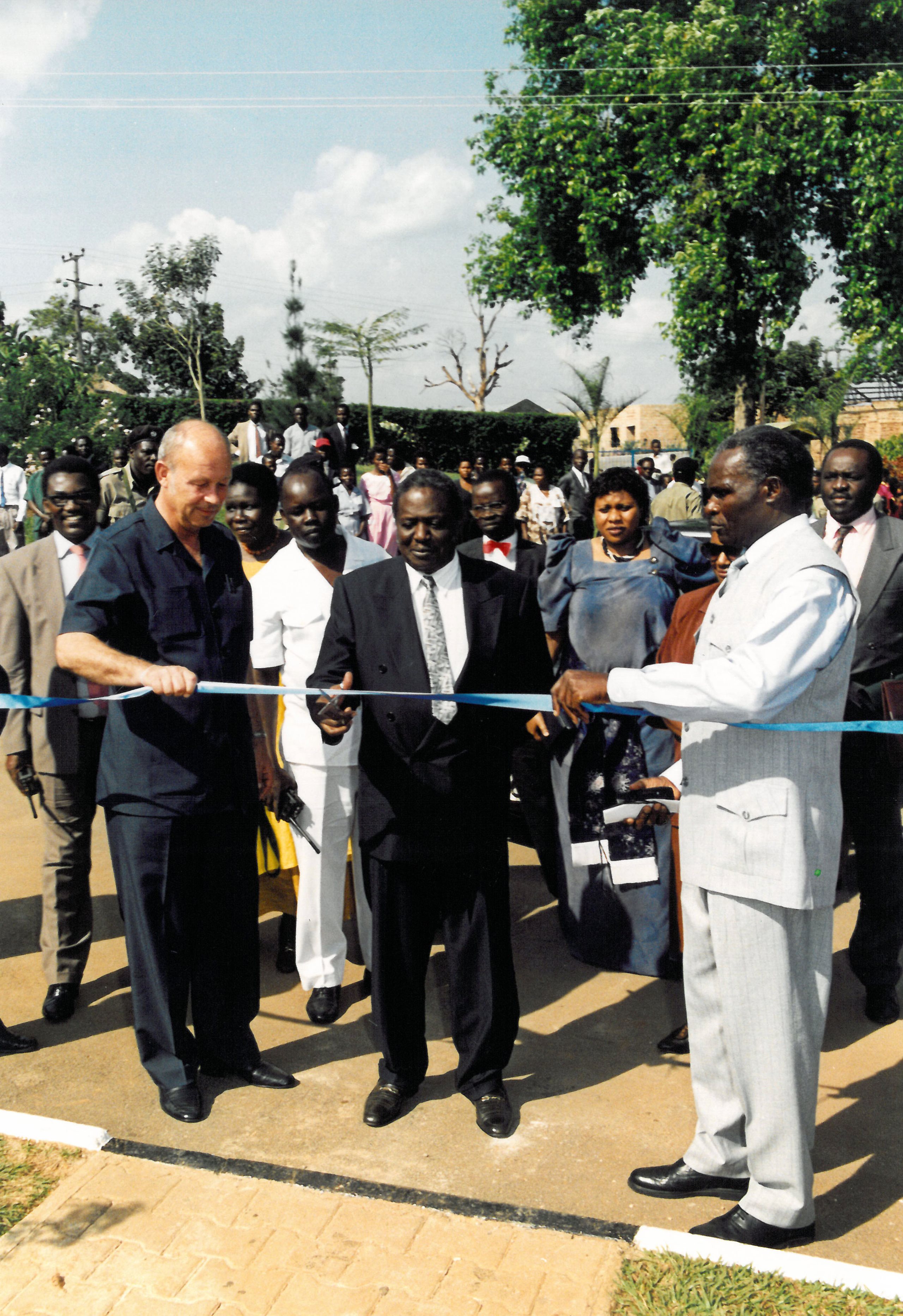 Einige Menschen hinter einem Absperrband, das gerade von einem von ihnen durchgeschnitten wird.