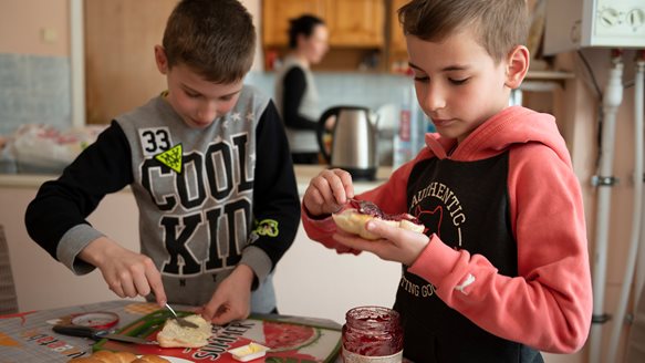 zwei Jungen schmieren sich Marmeladebrote