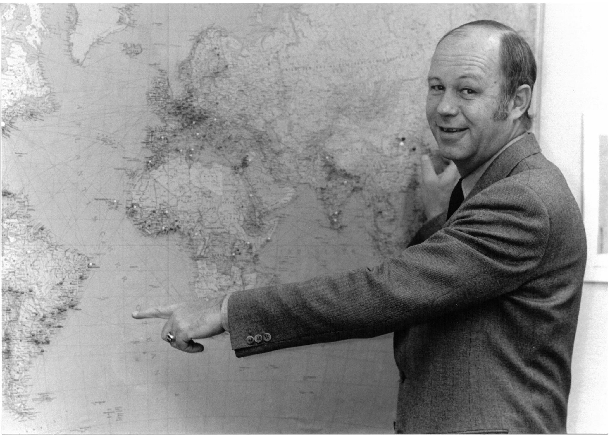 Helmut Kutin zeigt auf eine Weltkarte, auf der einige Punkte eingezeichnet sind