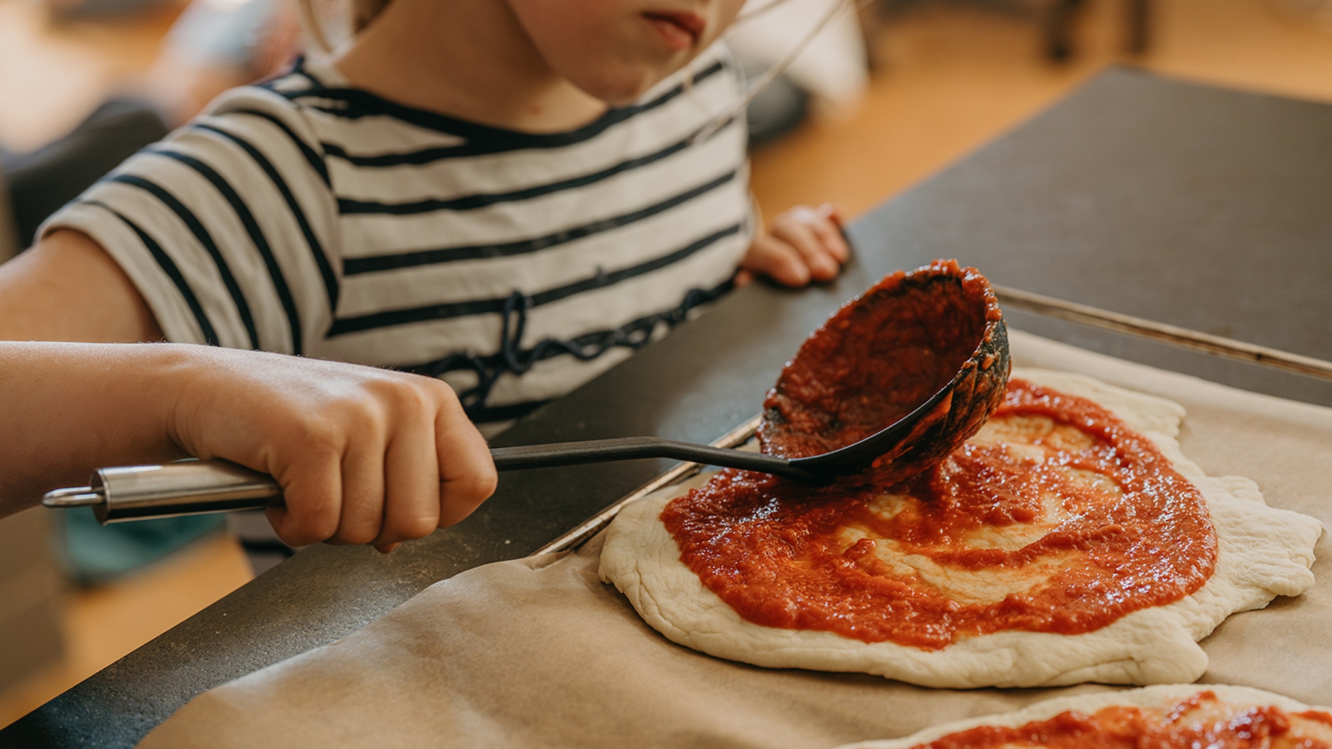 Kind beim Pizza machen