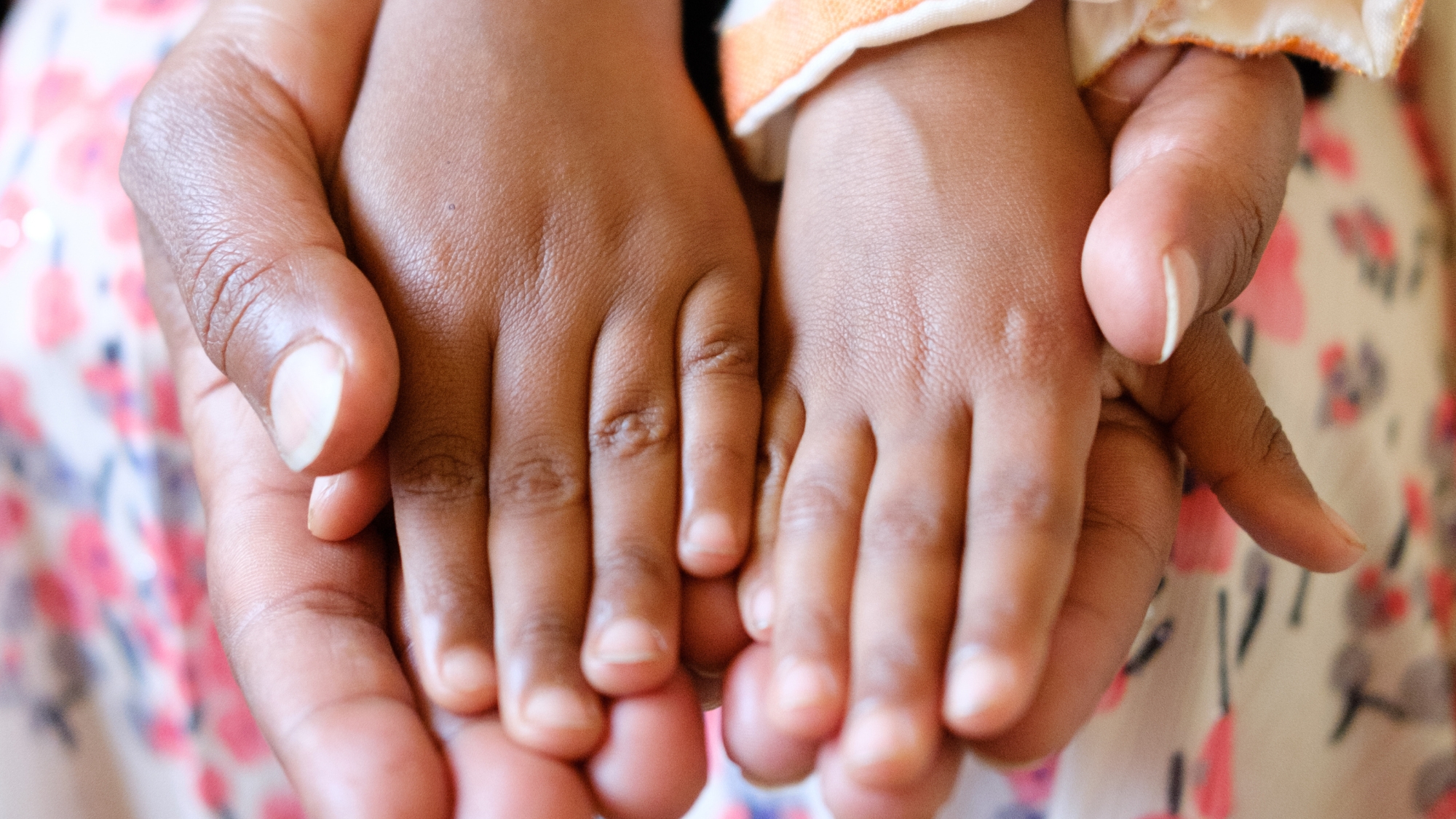Zwei Kinderhände in den Händen ihrer SOS-Kinderdorf-Mutter