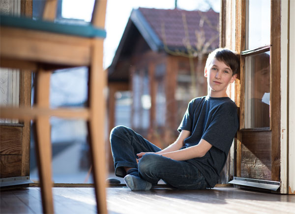 Bub lehnt an Wand und schaut in die Kamera