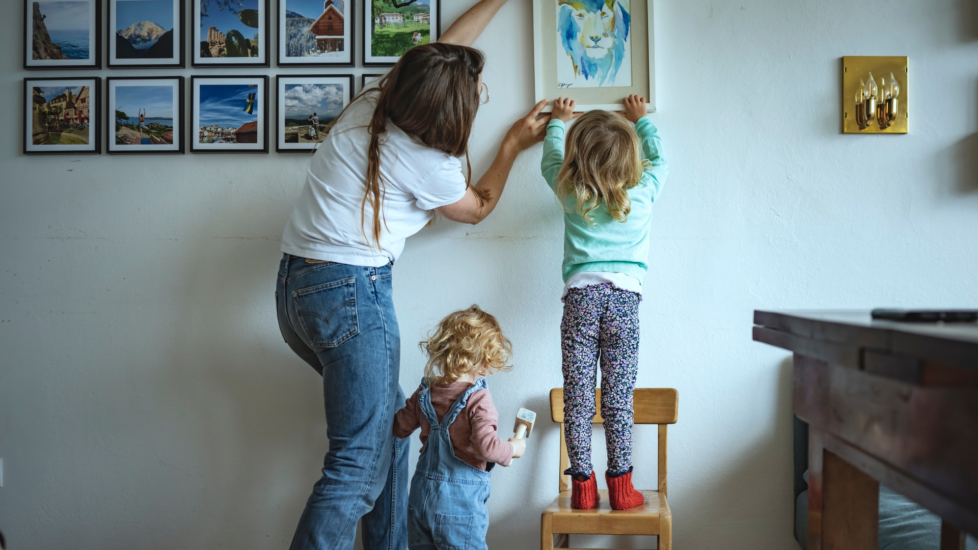 Eine Frau hängt mit zwei Kindern ein Bild auf
