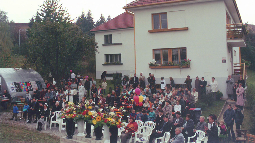 Große Festgemeinde sitzt vor einem großen Wohnhaus